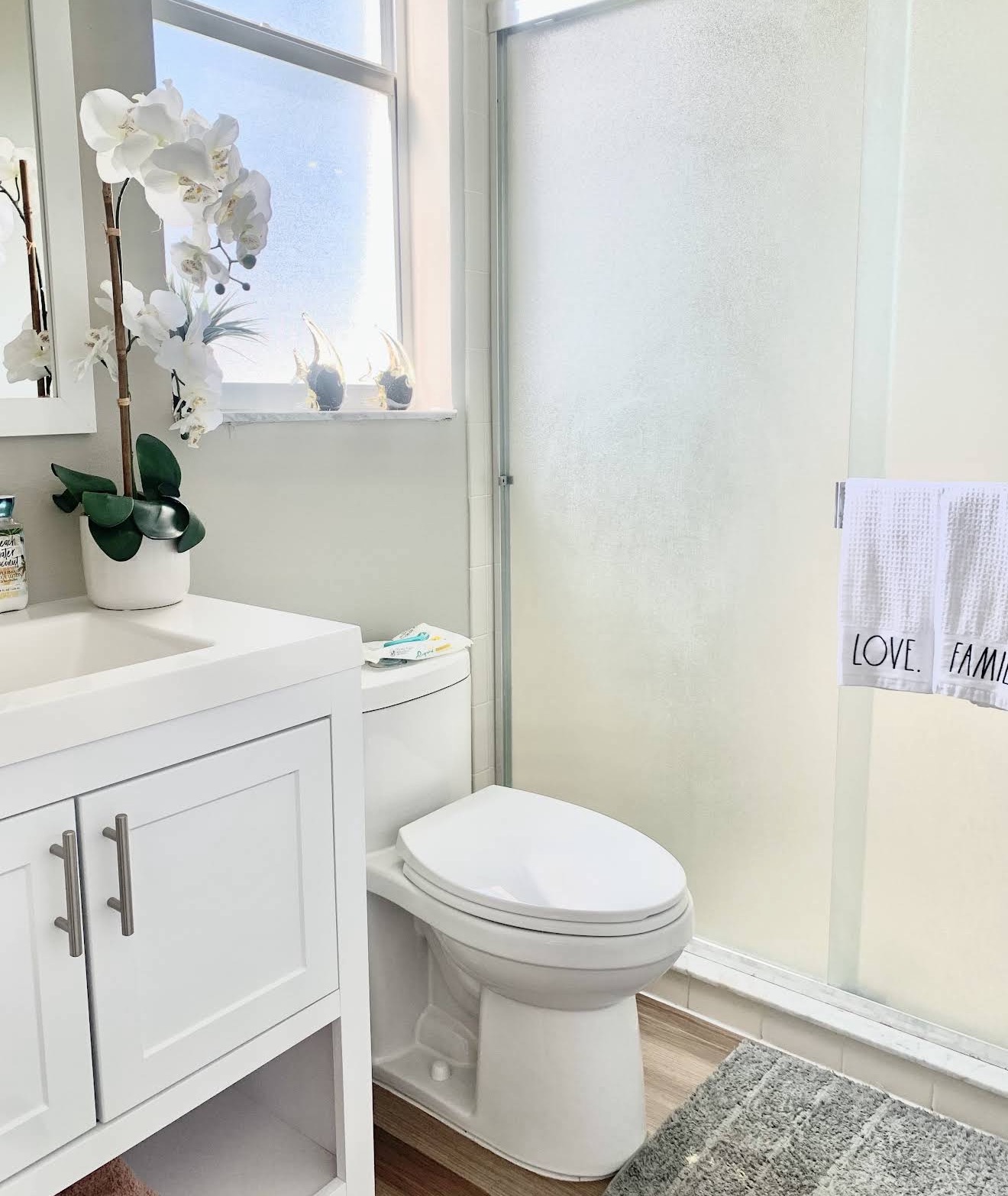 Spotless bathroom with white vanity and frosted glass shower